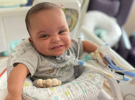 Baby in play seat, smiling at camera
